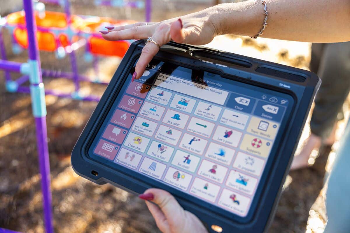 Woman using finger to select a symbol on the TD Navio touch screen AAC device.
